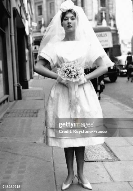 Mannequin présentant une robe de mariée courte en moire blanche à Londres, Royaume-Uni, le 12 mai 1959.