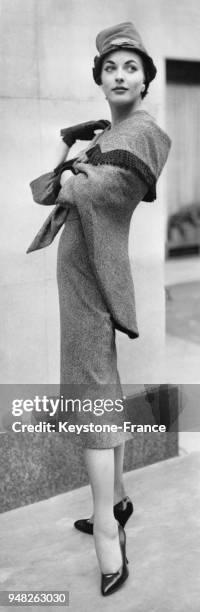 La mannequin Lois James présente un modèle Matita de la Collection Hiver 1956/1957: une robe en tweed marron et blanche portée avec une étole à...