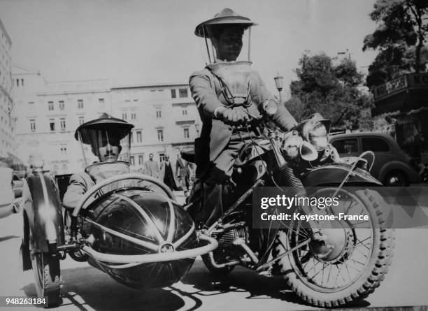 Motard et son passager dans le side-car portant le casque de moto créé par une entreprise grecque pour se protéger du vent et de la pluie, à Londres,...