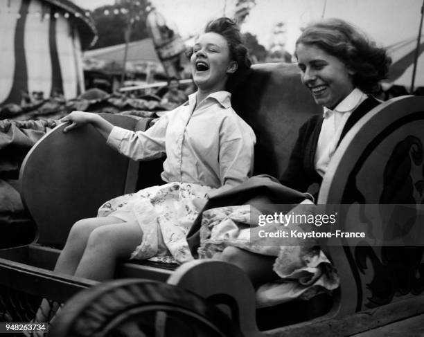Deux jeunes femmes s'amusent dans la chenille à la fête foraine de Battersea le 3 août 1959 à Londres, Royaume-Uni.