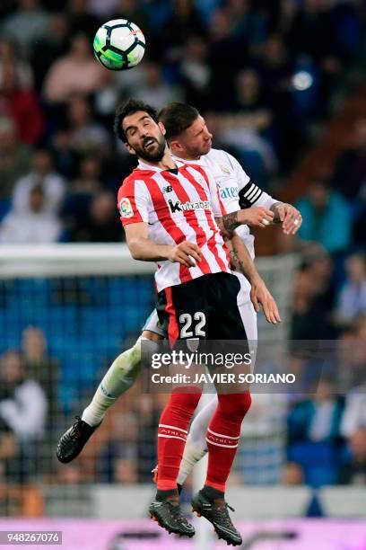 Athletic Bilbao's Spanish midfielder Raul Garcia jumps for the ball with Real Madrid's Spanish defender Sergio Ramos during the Spanish league...