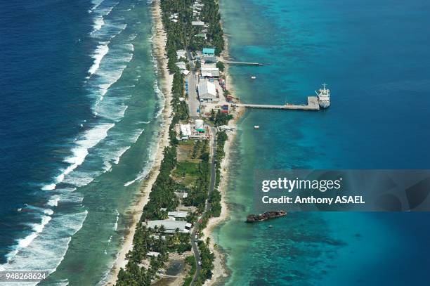 Tuvalu, Funafuti, aerial view of shoreline along the landscape with trees and houses and boat anchored by jetty.