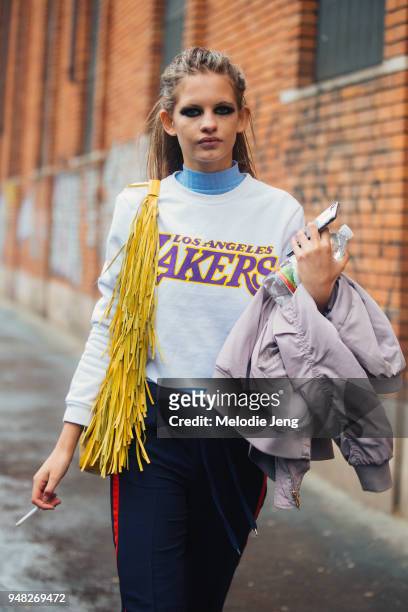 South African model Ansolet Rossouw wears dark eye makeup, a yellow fringe bag and a white Los Angeles Lakers basketball shirt after the Max Mara...