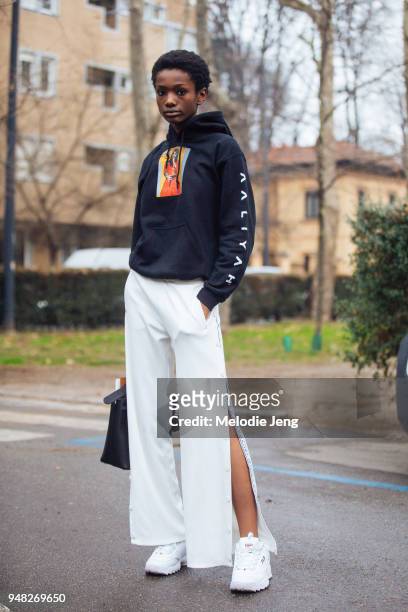 Model Imari Karanja wears a black Aaliyah hoodie, white Tory Burch button pants, and white chunky disruptor Fila sneakers during Milan Fashion Week...