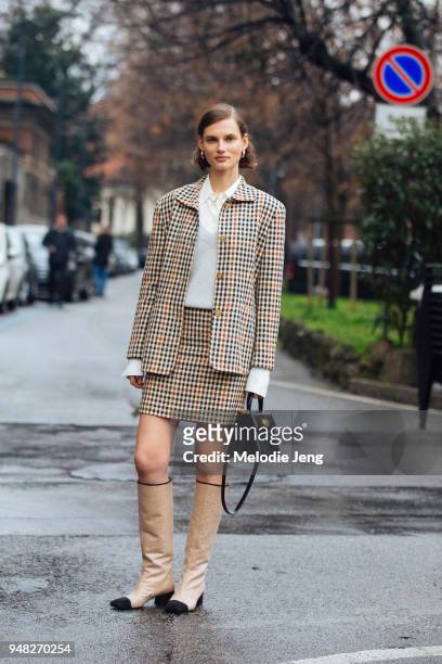 Lithuanian model Giedre Dukauskaite wears a matching checkered suit jacket and skirt, a white blouse, gray sweater, a black Bvlgari bag, and gold...