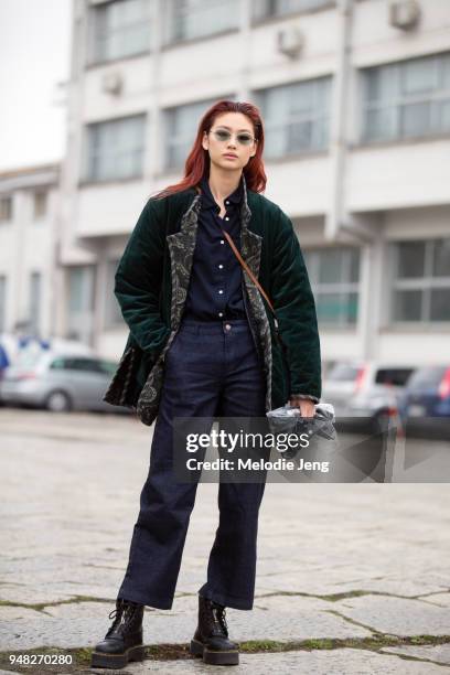 Korean model Hoyeon Jung wears a green sunglasses, a green velvet jacket over a blue top, jeans, and black boots during Milan Fashion Week...