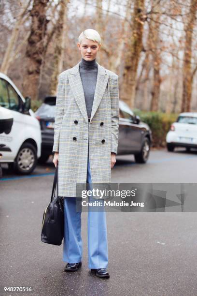 Model Sarah Fraser gray and yellow tartan jacket, a black purse, blue trousers, and black shoes wears a during Milan Fashion Week Fall/Winter 2018/19...