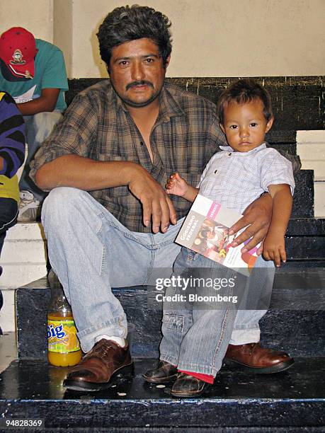 Rubin Cortes, 41 and his son Uriel, 1 1/2, sit for a portrait as they wait for their wife and mother to pick up a monthly stipend from the social...