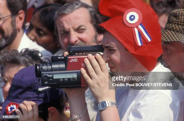 Un homme coiffé d'un bonnet phrygien filme avec sa caméra la reconstitution des Etats Généraux de 1789 le 4 mai 1989 à Versailles, France.