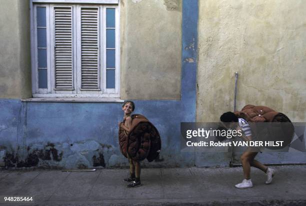 Jeunes garçons transportant des matelas sur leur dos en janvier 1988 à La Havane, Cuba.