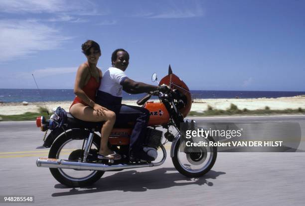 Un homme à moto et sa passagère en maillot de bain sur une route en bord de mer en août 1987 à Cuba.