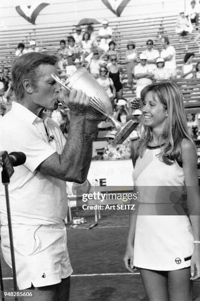 Charlton Heston boit du champagne dans le trophée du tournoi 'Charlton Heston Tennis Classic' avec l'actrice Robin Evans en mai 1981 à Palm Beach,...