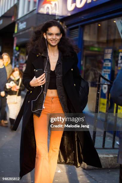 Model Nikki Vonsee listens to music with a single headphon and wears the eyemakeup after the Halpern show, a long black coat over a black denim...