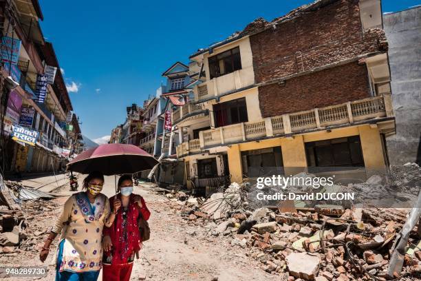 Deux femmes avec un parapluie marchant au milieu des gravats et maisons détruites, après le tremblement de terre, le 4 mai 2015, Kathmandu, Népal.