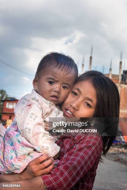 Une fillette tenant un bébé dans ses bras après le tremblement de terre, le 3 mai 2015, village de Bungamati, vallée de Kathmandu, Népal.