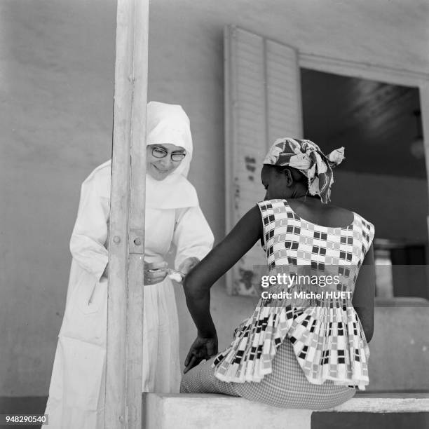 Infirmière religieuse vaccinant une patiente dans au centre hospitalier de l'Institut Marchoux à Bamako, circa 1950, Mali.