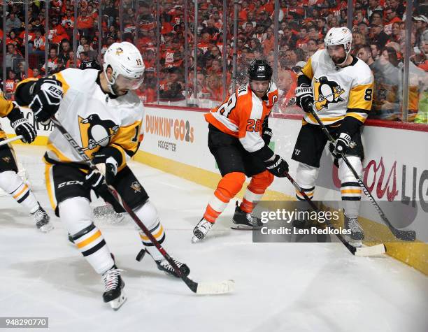 Claude Giroux of the Philadelphia Flyers battles for the loose puck Brian Dumoulin and Derick Brassard of the Pittsburgh Penguins in Game Three of...