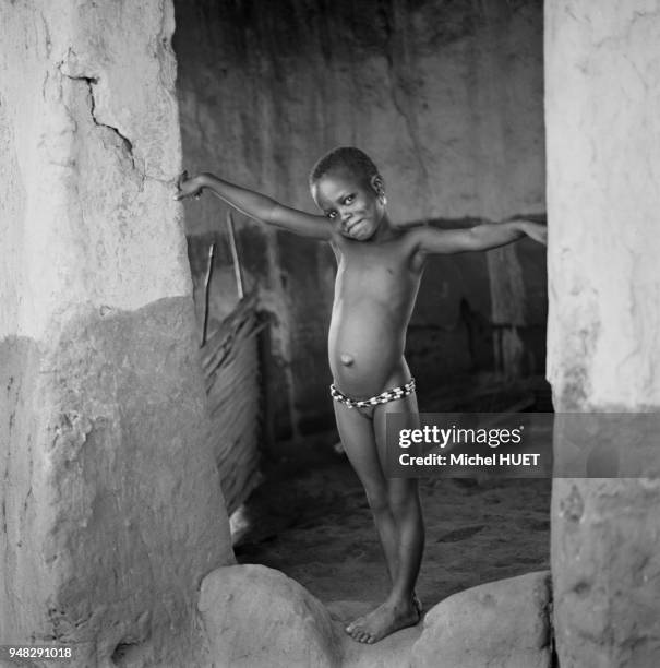 Enfant à l'entrée de sa maison dans le village lacustre de Ganvié, circa 1950, Bénin.