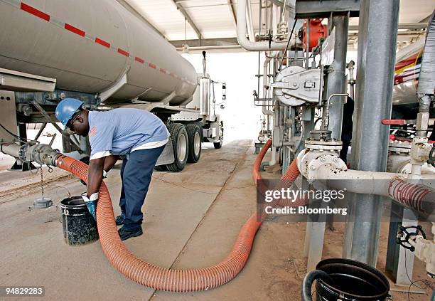 Tractor-trailer driver Quincy Miller prepares to disconnect a hose from his truck after delivering ethanol to a pumping station at the Motiva...