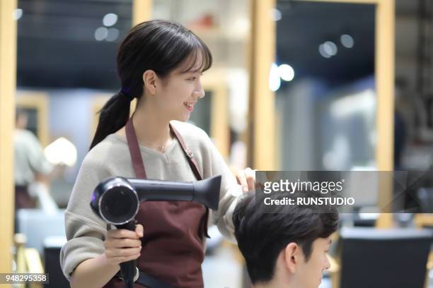hairdresser blow drying customer's  hair in salon - hand holding hair dryer stock pictures, royalty-free photos & images