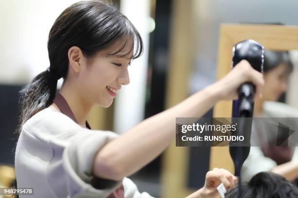 hairdresser drying customer's hair in salon - young woman hair cut photos et images de collection
