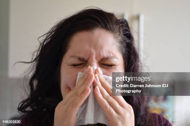 woman blowing her nose hard into a tissue at home - grippevirus typ a stock-fotos und bilder