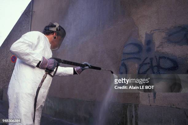 Employé du service de propreté de la municipalité de Nantes nettoyant des graffitis au karcher sur un mur, en février 1992, en Loire-Atlantique,...