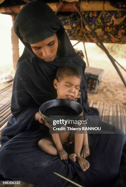 Femme faisant boire son enfant pendant lors la famine provoquée par la sécheresse dans le Sahel, en février 1984, Mauritanie.
