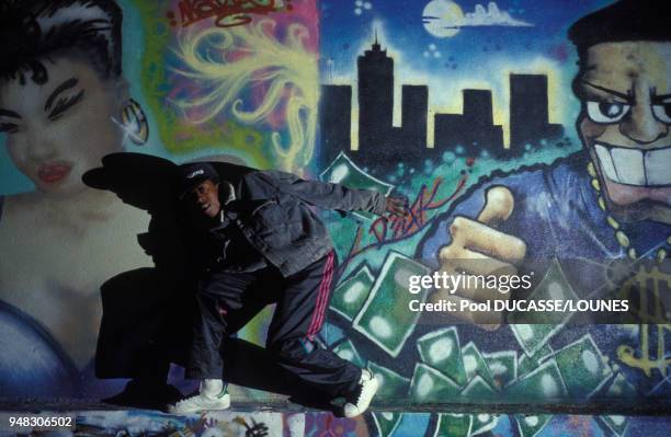 Jeune posant devant un mur de graffitis dans la rue à Saint-Denis, en Seine-Saint-Denis, le 10 décembre 1990, France.