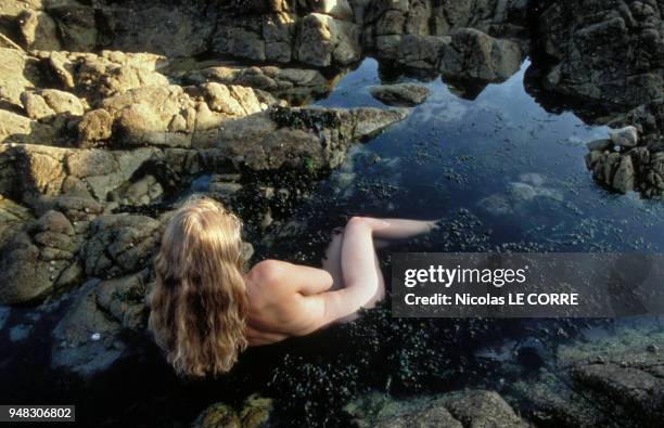 Femme prenant un bain d'algues dans les rocher.