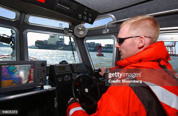 Cory Helmerson, a U.S. Coast Guard boatswain's mate second class, pilots a 25-foot Coast Guard boat patrolling past a container ship in the port of...