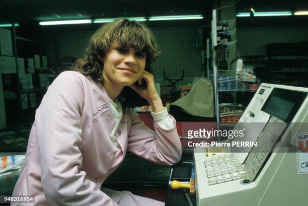La footballeuse Sylvie Saunier dans l'exercice de sa profession de caissière dans un supermarché le 1er mars 1984 à Moulins, France.