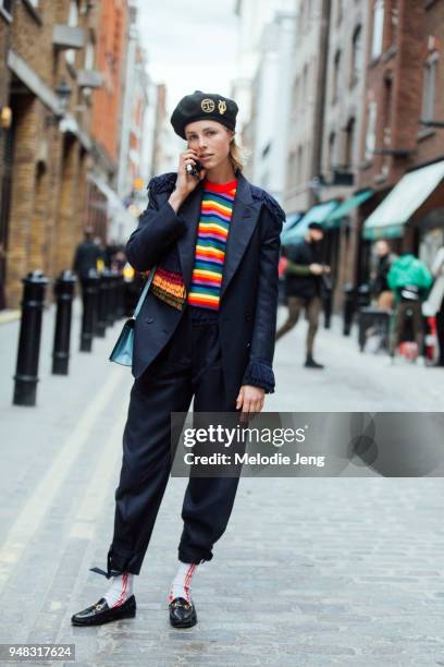 Model Edie Campbell talks on the phone and wears an Itchy Scratchy Patchy "Lyre & Scales Tam o’Shanter" Black wool tam hat with military goldwork...