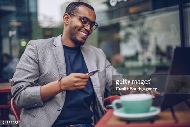 mann mit laptop im café - credit card stock-fotos und bilder
