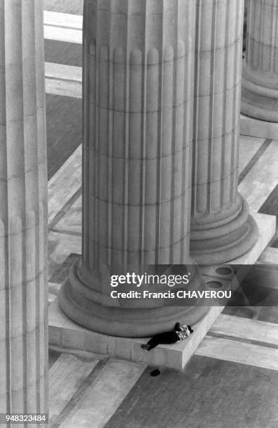 Homme endormi au pied d'une colonne de la basilique Notre-Dame de la Paix à Yamoussoukro, en juin 1993, Côte d?Ivoire.