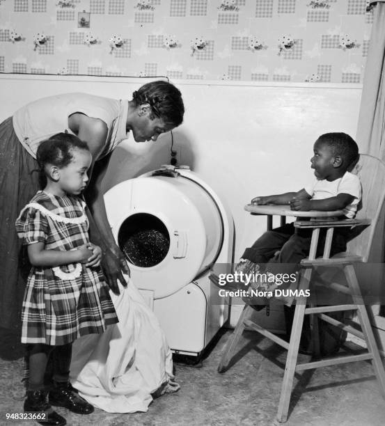 Une mère de famille lave du linge en présence de ses enfants à Dallas au Texas aux Etats-Unis vers 1950.