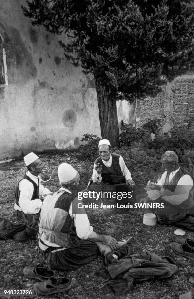 Hommes âgés discutant dans un jardin à Shkodër, en août 1964, Albanie.