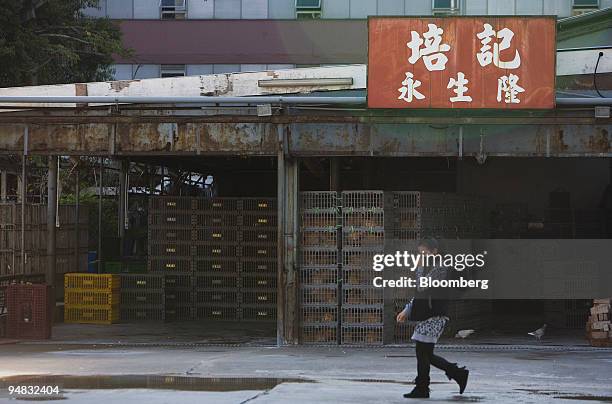 Woman covers her face as she walks past live chickens at the Cheung Sha Wan wholesale market in Hong Kong, China, on Wednesday, Dec. 10, 2008. Hong...