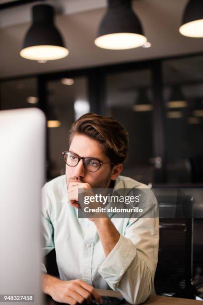 young men sitting at work and using computer - hand on chin stock pictures, royalty-free photos & images