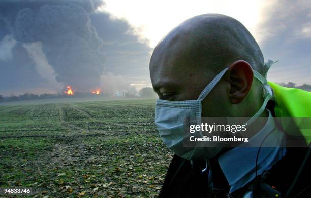 Police officer patrols the perimeter as flames and smoke rise over the Buncefield Fuel Depot in Hemel Hempstead, England, Sunday, December 11, 2005....