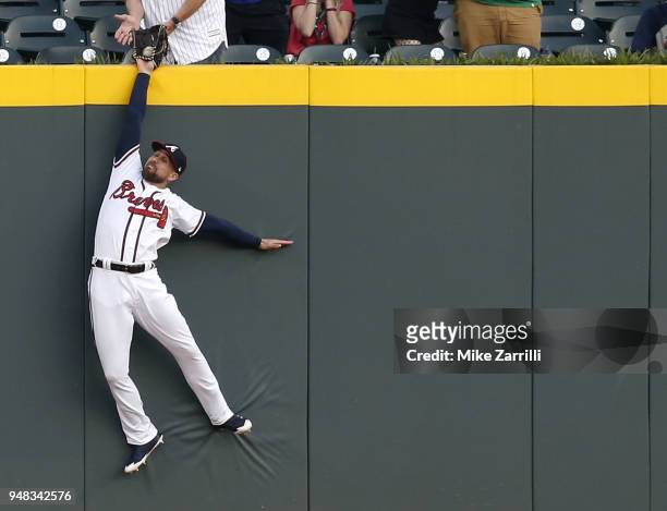 Centerfielder Ender Inciarte of the Atlanta Braves catches a ball over the outfield wall to rob a home run from Philadelphia Phillies left fielder...