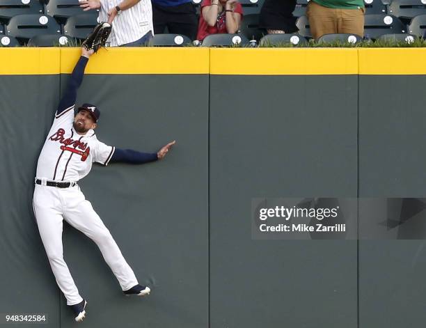 Centerfielder Ender Inciarte of the Atlanta Braves catches a ball over the outfield wall to rob a home run from Philadelphia Phillies left fielder...