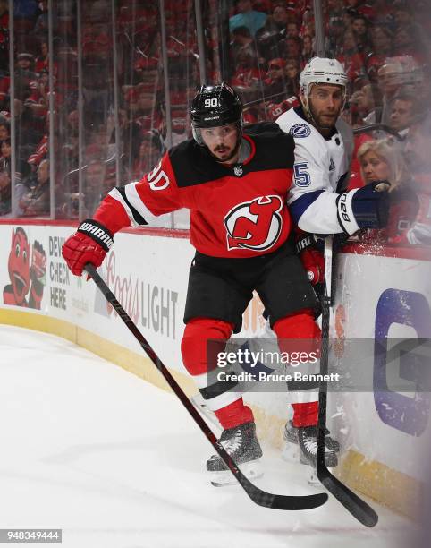 Marcus Johansson of the New Jersey Devils hits Dan Girardi of the Tampa Bay Lightning into the boards during the second period in Game Four of the...
