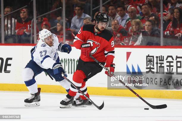 Marcus Johansson of the New Jersey Devils plays the puck as Ryan McDonagh of the Tampa Bay Lightning defends him in Game Four of the Eastern...