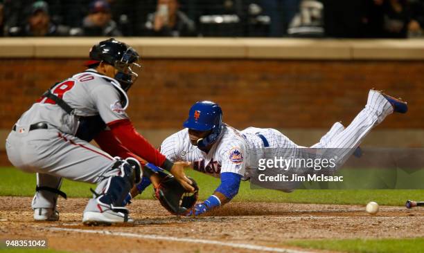 Yoenis Cespedes of the New York Mets dives home for a run in the eighth inning ahead of the throw to Pedro Severino of the Washington Nationals at...