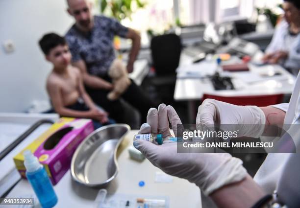 Family physician prepares a measles vaccine during a consultation on April 16, 2018 in the Romanian capital, Bucharest. - Measles still claims young...