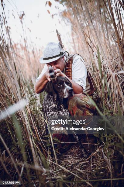 hunter with his dog hiding in the reed waiting for action - hobby bird of prey stock pictures, royalty-free photos & images