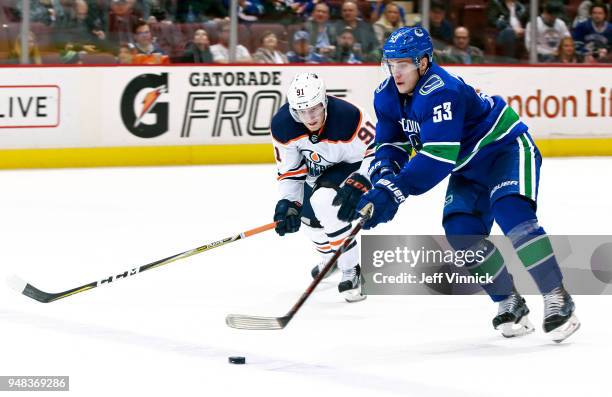 Drake Caggiula of the Edmonton Oilers looks on as Bo Horvat of the Vancouver Canucks skates up ice with the puck during their NHL game at Rogers...