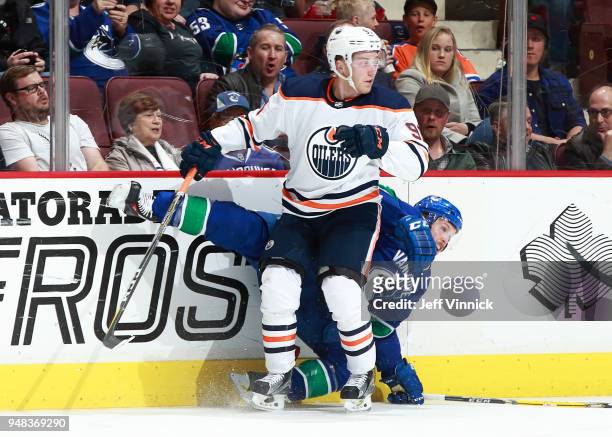 Drake Caggiula of the Edmonton Oilers checks Alex Biega of the Vancouver Canucks during their NHL game at Rogers Arena March 29, 2018 in Vancouver,...