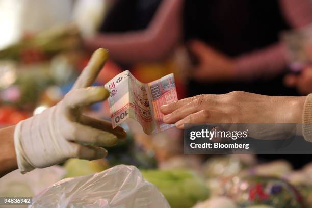 Vendor accepts a HK$100 banknote at a wet market in Hong Kong, China, on Saturday, Dec. 20, 2008. Hong Kong's inflation accelerated for the first...